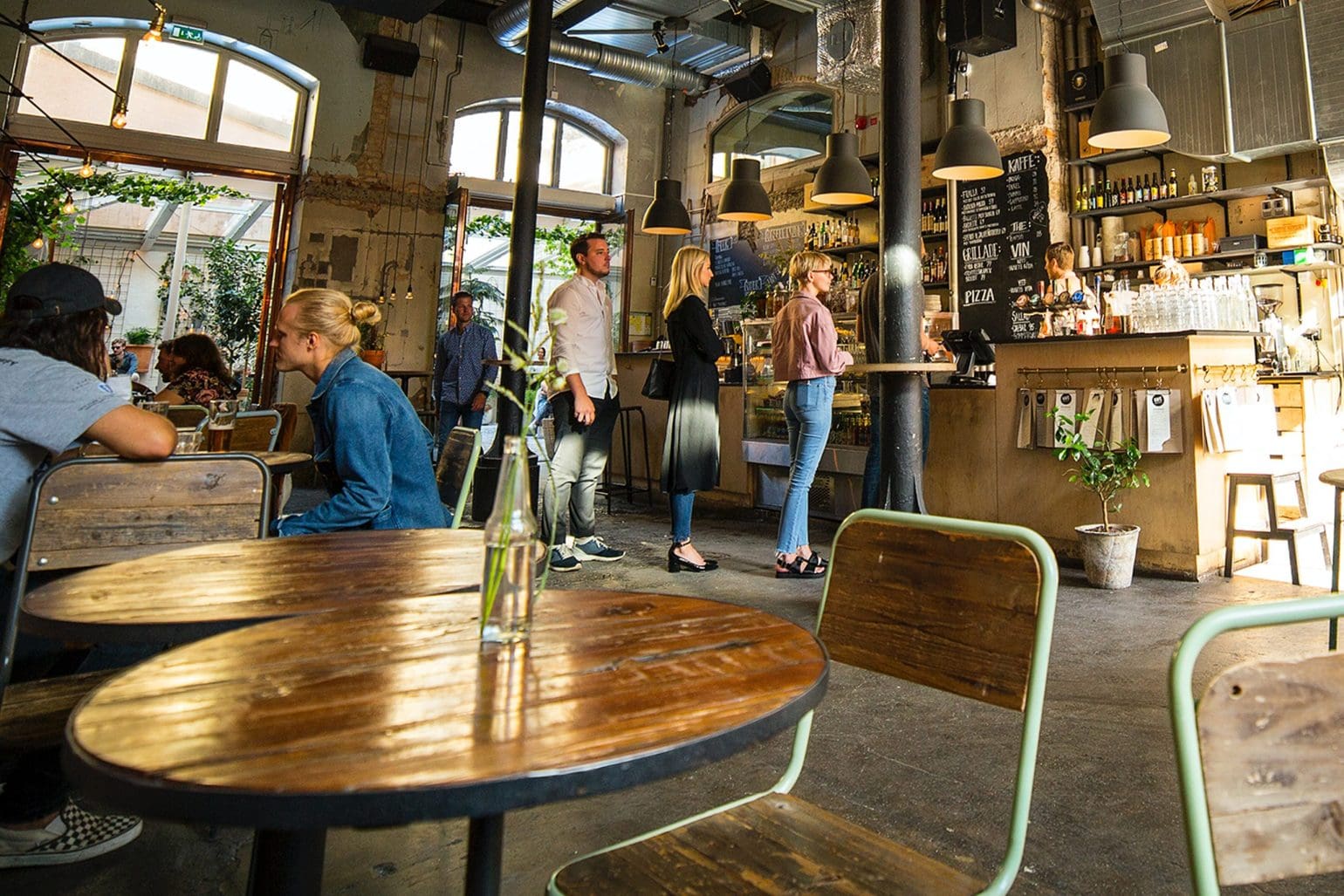 billede af en cafe hvor nogle mennesker står i kø og andre som sidder og nyder deres drink